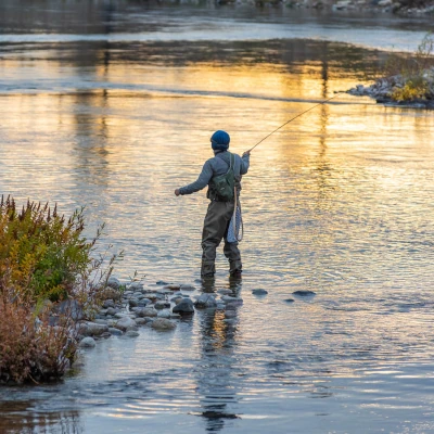 A fly fisherman casting into a river.