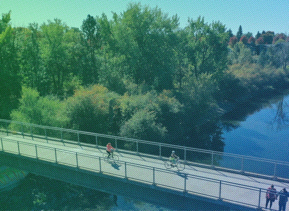 Two cyclists cross a bridge over the Spokane River