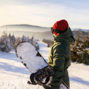 A snowboarder admiring the view on a snow-covered mountain.