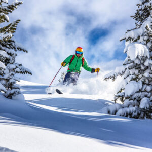 A skier plowing through powder on a bright sunny day.