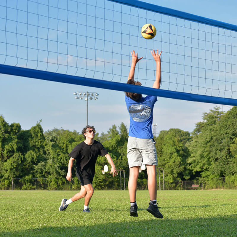 A person setting a volleyball for a teammate to spike.