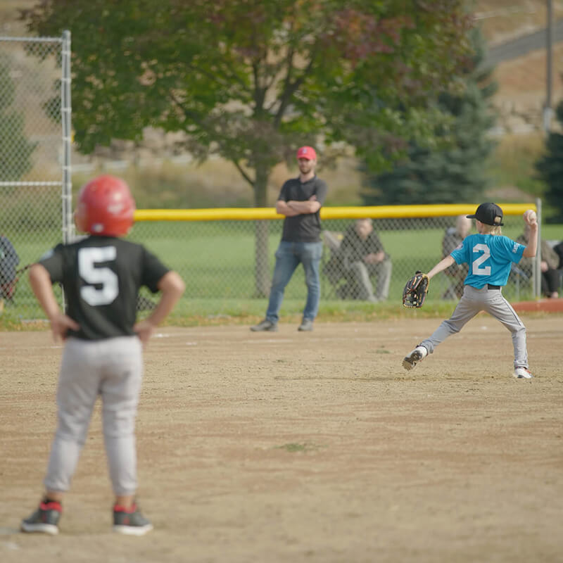 A kid throwing a baseball to home base.